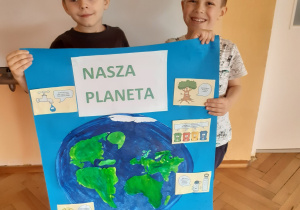 Kostek i Antek prezentują wspólnie wykonany plakat " Ziemia, nasza planeta".
