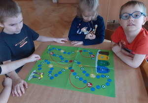 Kostek, Lenka i Ignacy grają w grę planszową " Recyklingowy wyścig