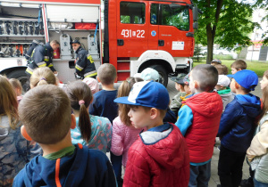 Przedszkolaki oglądają wyposażenie wozu strażackiego.