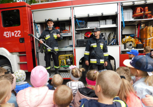 Jeden ze strażaków pokazuje przedszkolakom narzędzie ratownicze "hooligan".