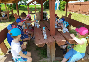 Dzieci jedzą pyszne bułeczki i piją wodę.