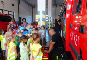 Pan strażak zapoznaje dzieci z wyposażeniem torby pierwszej pomocy