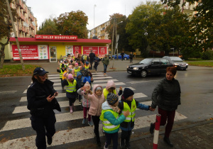 Dzieci przechodzą przez ulicę z podniesioną ręką.