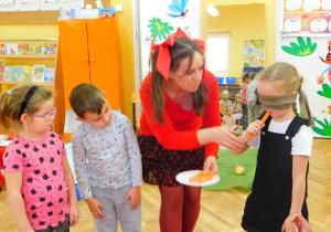 Dzieci z Żabek biorą udział w konkursie - "Zgadnij po smaku". Laura z zawiązanymi oczami próbuje marchewki.