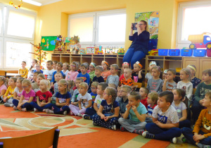 Dzieci siedzą na widowni i oglądają występ swoich pań.