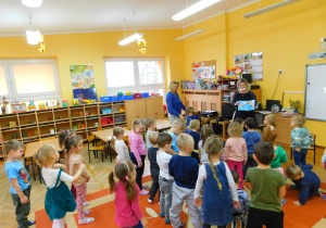Dzieci podczas zabawy pt. "Kolory". Wstały przedszkolaki, które mają kolorowe ubranie.