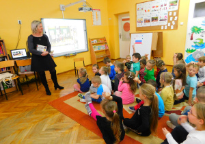 Dzieci podczas zabawy pt. "Kolory". Przedszkolaki podnoszą rękę do góry, które mają ubranie w wymienionym w języku rosyjskim kolorze.