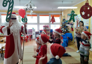 Dzieci żegnają Mikołaja i proszą, żeby za rok też do nich przyjechał.