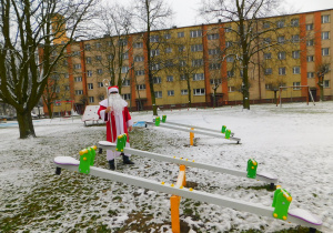 Mikołaj z obdarowanymi huśtawkami ważkami w ogrodzie przedszkolnym.