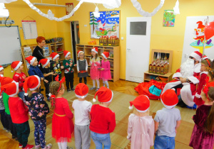 Dzieci z gr. II, stojąc przed Mikołajem, śpiewają i grają na instrumentach.