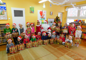 Wszystkie Krasnoludki, z otrzymanymi paczkami, ustawione do wspólnej fotografii z Mikołajem.