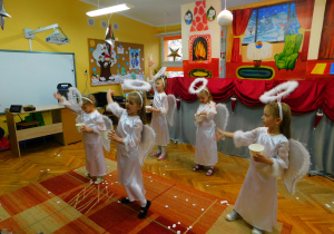 Dziewczynki w strojach aniołków tańczą układ taneczny do piosenki „Zaczarowany śnieg”.