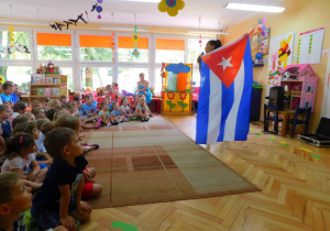 Pani Patrycja pokazuje przedszkolakom flagę kubańską.