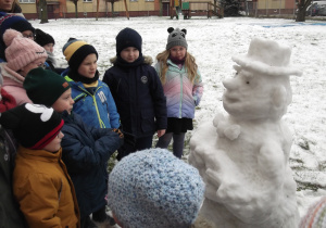 Dzieci oglądają rzeźbę ze śniegu.