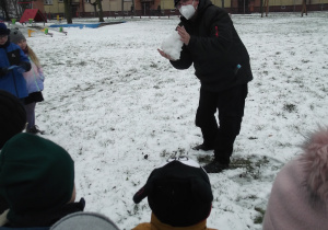 Pan Tomasz pokazuje dzieciom w jaki sposób uzyskać czysty śnieg.