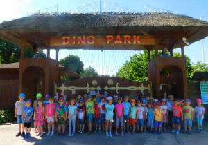 Dzieci stoją przed bramą wejściową do Dino-parku.