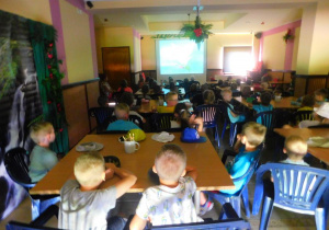 Przedszkolaki oglądają bajki o dinozaurach.