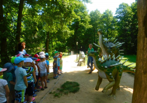 Przedszkolaki oglądają naturalnej wielkości figury dinozaurów.
