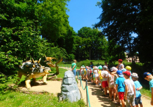 Przedszkolaki oglądają naturalnej wielkości figury dinozaurów.