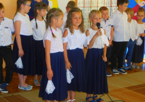 Hania W. trzyma mikrofon i z Anią i Gabrysią recytują wiersz.