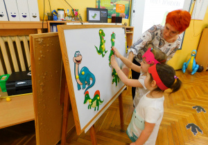 Biedronki: Oliwka i Lenka dopasowują na tablicy połówki dinozaurów.