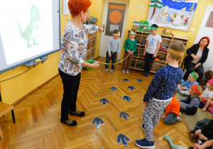 Pani Agnieszka pokazuje, za pomocą miarki, wielkość śladów dinozaura.