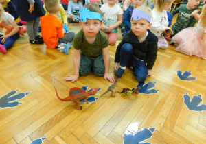Chłopcy z gr. Biedronek: Grzesiu i Nikodem układają figurki dinozaurów od najmniejszego do największego.