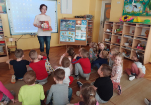 Pani Ilona czyta dzieciom książkę i pokazuje ilustracje.
