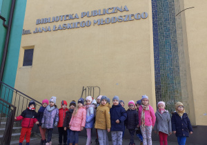 Grupa Krasnoludków stoi przed Biblioteką Publiczną w Łasku.