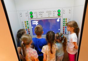 Dzieci oglądają planety w stacji kosmicznej.