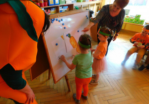 Biedroneczki, najmłodsze przedszkolaki układają puzzle z obrazkiem marchewki.