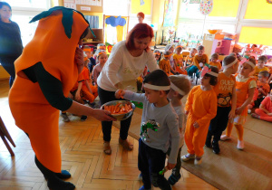 Pani Marchewka i pani Dyrektor częstują dzieci z Żabek marchewkami i soczkami marchwiowymi.