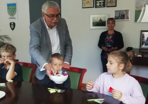 Pan Burmistrz częstuje dzieci cukierkami.