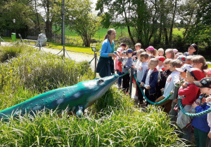 Dzieci słuchają wyjaśnień przewodniczki, że ten prehistoryczny gad to nie krokodyl.