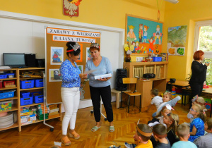 Pani Renia na ręce nauczycielek daje malowanki dla dzieci.