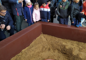 Pani dyrektor Barbara Nowakowska wraz z dziećmi: Gabrysią, Zosią i Filipem przyglądają się zakopywaniu Kapsuły Czasu.