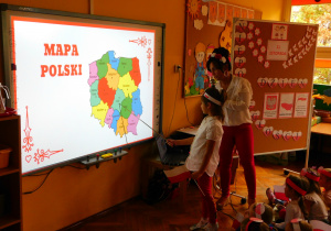 Hania z grupy Krasnoludków wskazuje na mapie Polski, gdzie leży Łask.