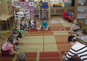 Przedszkolaki z panią Agnieszką pokazują grę na bębenku.
