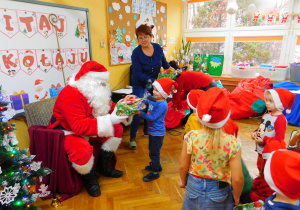 Mikołaj wręcza prezent Kasjanowi z grupy Misiaczków.