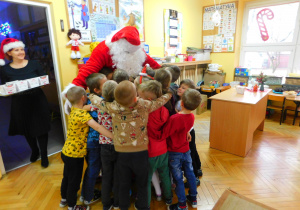 Dzieci z grupy Krasnoludków przytulają się do Mikołaja.