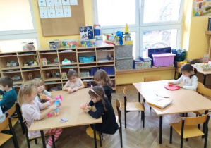 Dzieci z grupy Żabek bawią się przy stolikach nowymi zabawkami.