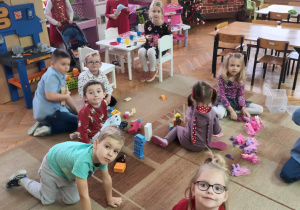 Dzieci z grupy Słoneczek bawią się na dywanie nowymi zabawkami.