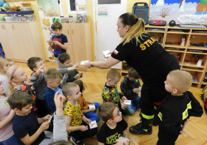 Pani Marta rozdaje dzieciom naklejki "Od dzieciaka do strażaka".