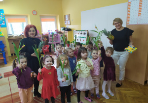 Dziewczynki z Biedronek z panią Anią i panią Dyrektor pozują do zdjęcia z kwiatami.