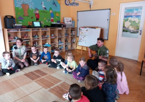 Przedszkolaki uważnie słuchają słów piosenki.