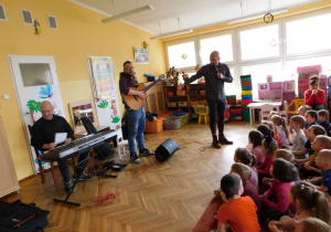 Paan Adam pokazuje dzieciom gitarę klasyczną.