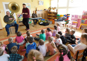 Dzieci słuchają dźwięków suzofonu wygrywanych przez pana Sławka.