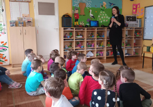 Przedstawicielka EKOREGIONU wyjaśnia dzieciom jakie odpady należy wrzucać do poszczególnych pojemników.