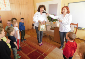 Pani Dorota obdarowuje przedszkolaków prezentem i zachęca do zabawy z poezją.