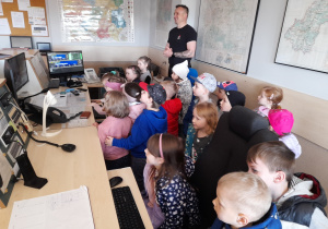 Pan Sławek pokazuje dzieciom pomieszczenie dyżurnego stanowiska kierowania.
